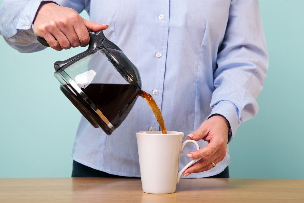 woman on her break pouring herself a mug of hot filtered coffe