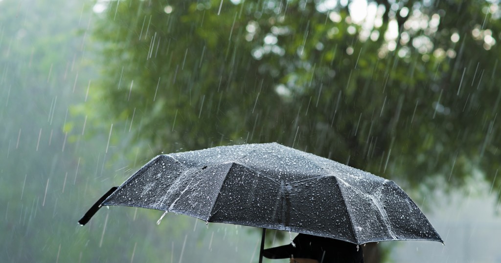A person holding an umbrella under heavy rain