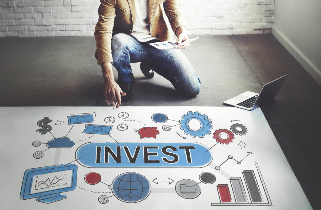 person in front of a poster with invest written