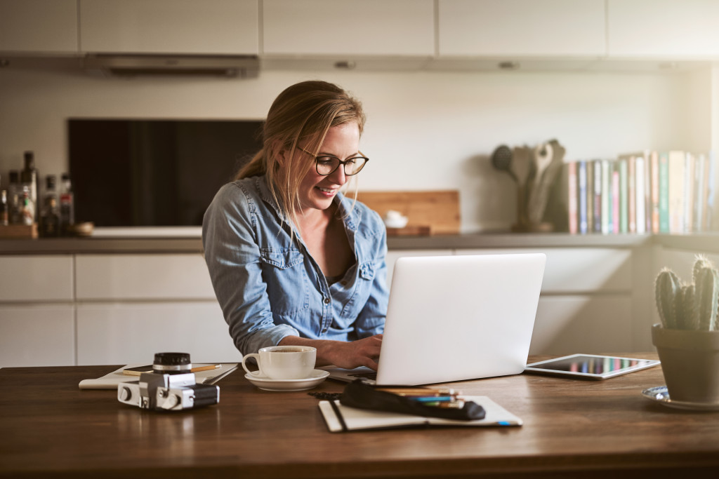 Portrait of a woman sitting in kitchen working on her laptop