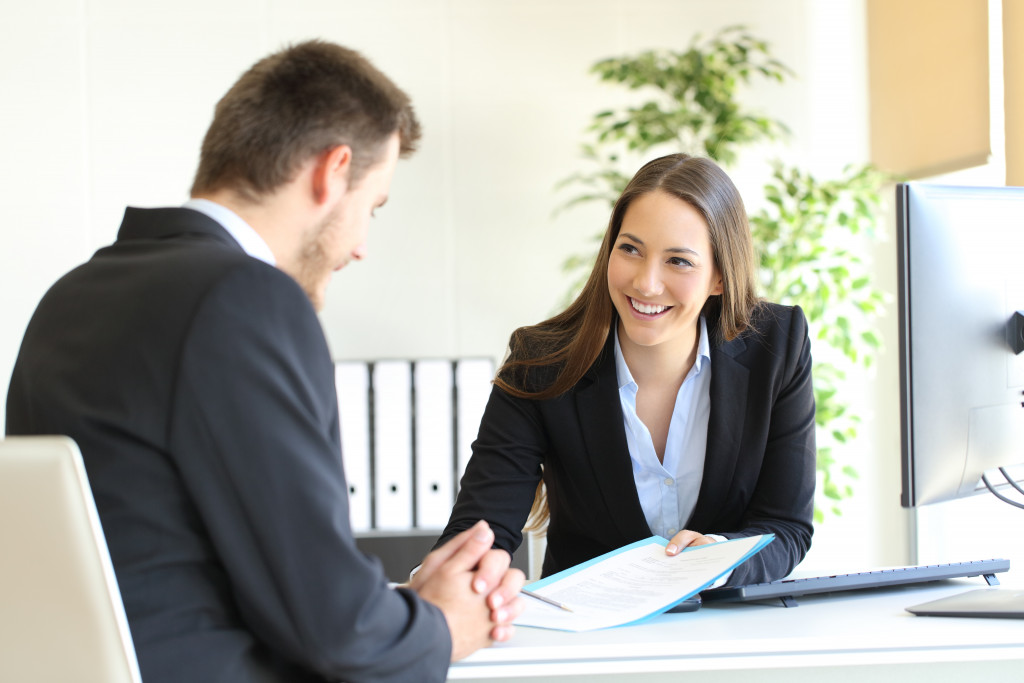 Female hiring staff interviewing a make candidate in an office.