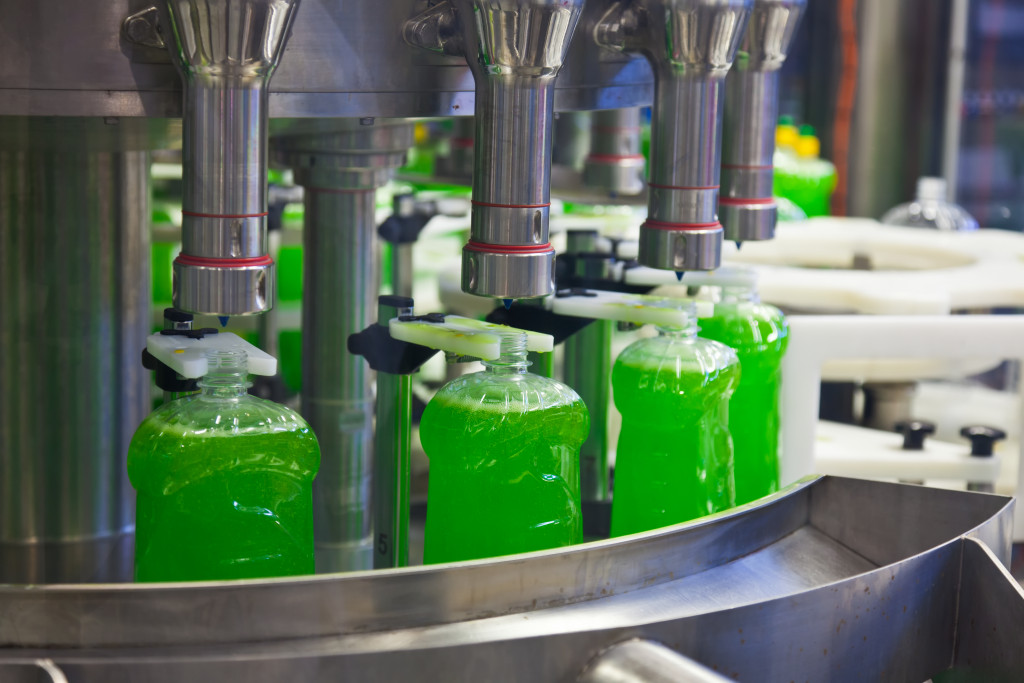 Bottles being filled with green liquid in a factory