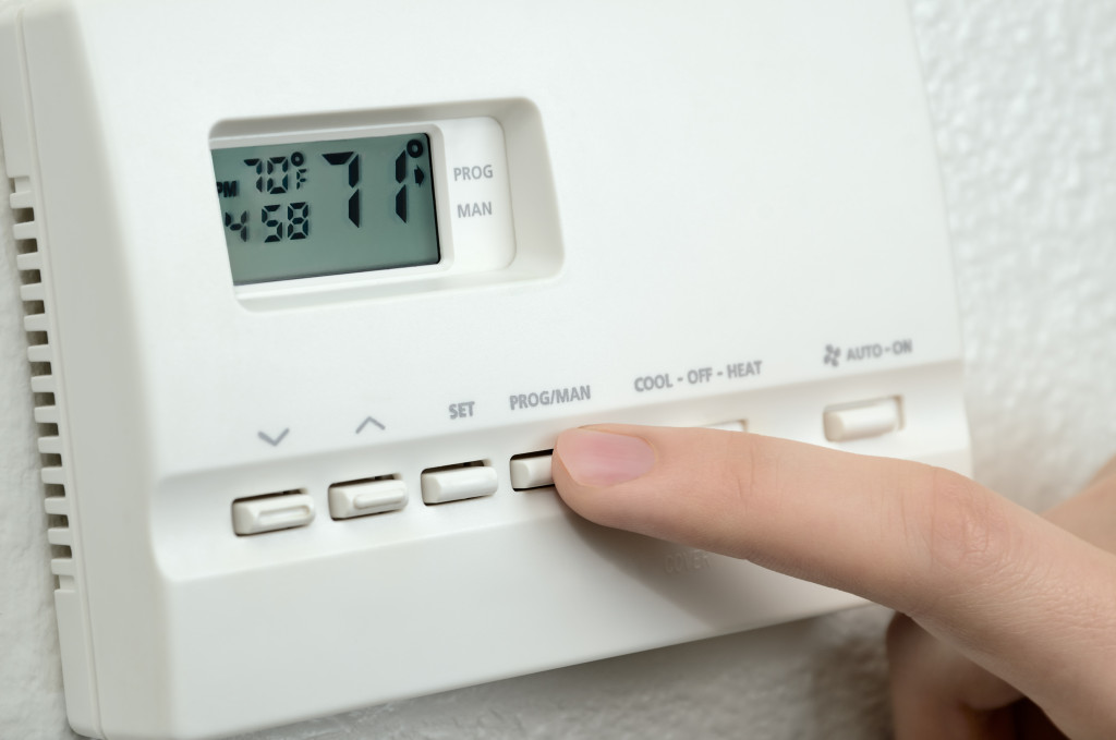 A finger pressing a thermostat button