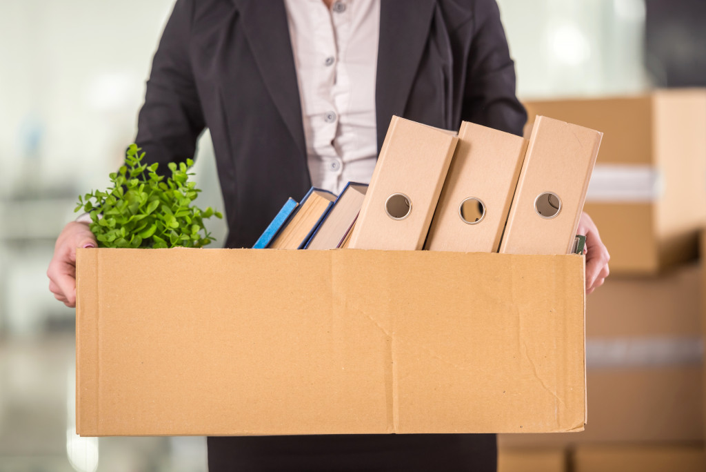 A professional holding a box of office supplies for moving