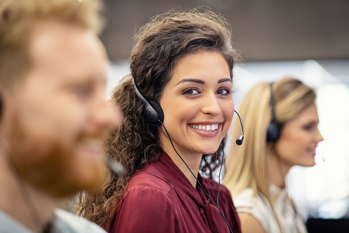 woman smiling while wearing headset in customer service office