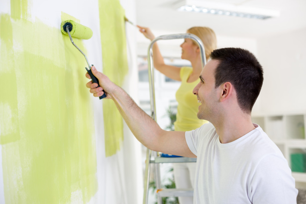 young couple painting home a bright color