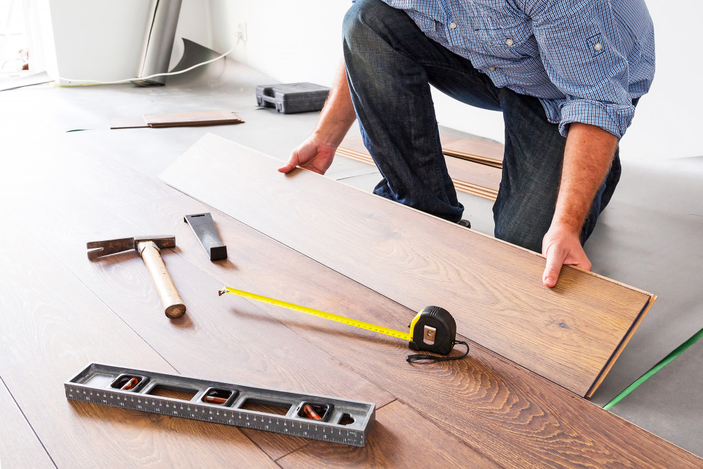 man installing wooden floor on a concrete floor for remodeling